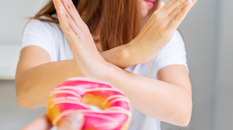 woman crossing arms in front of donut