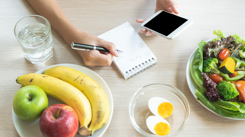 person writing down their food intake on a notebook