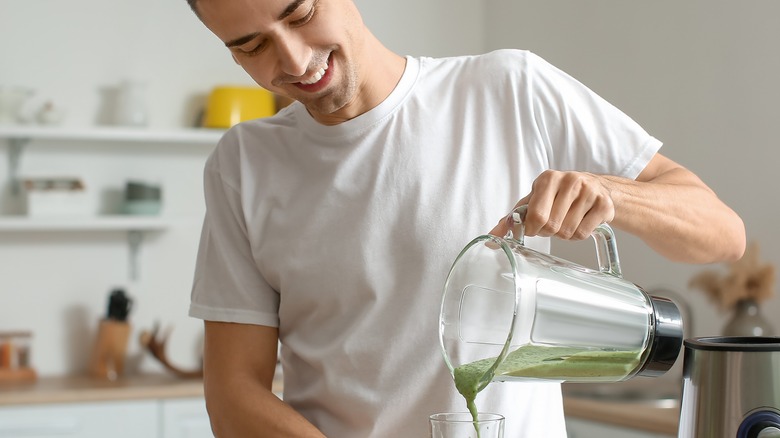 Young man pouring green drink 