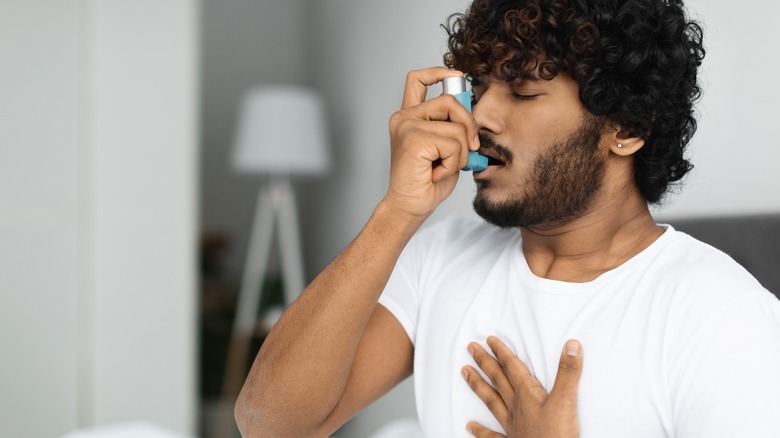 man using inhaler in bed
