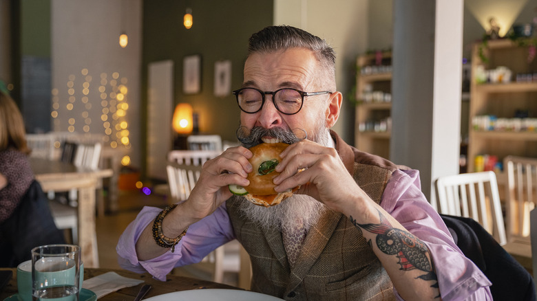 Man with mustache eating sandwich