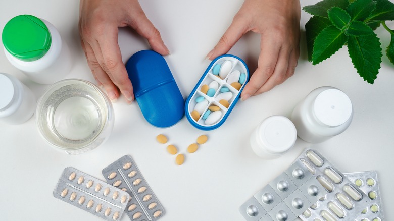 Hands holding open pill storage container