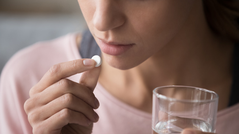 White woman about to take a pill