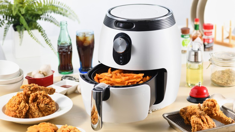 an air fryer surrounded by air fried food