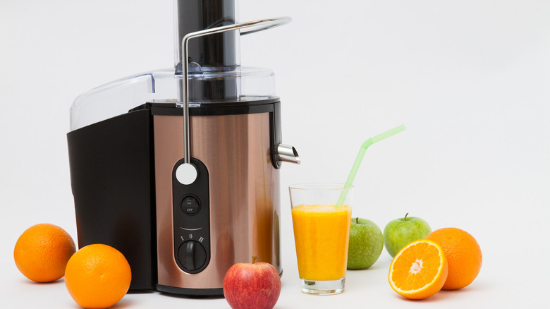 a juicer with fruits next to it