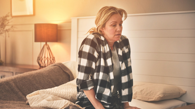 woman uneasy sitting up in bed in the morning