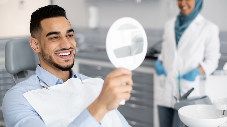 Man smiling in hand mirror
