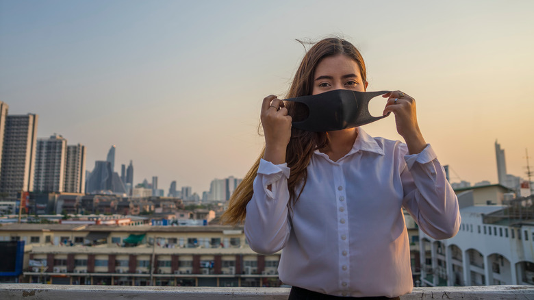 Woman holding mask outside