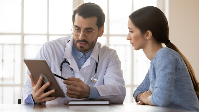 doctor holding tablet and talking to patient