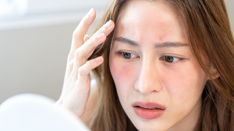 Woman looking at face in mirror