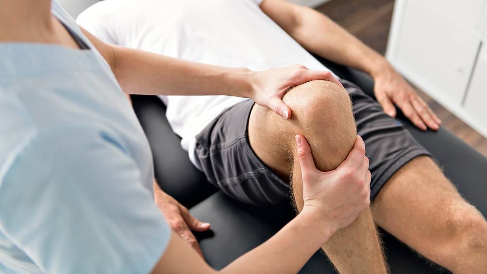 Physiotherapist helping patient with leg exercises