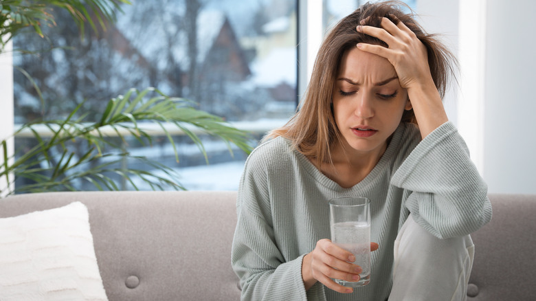 woman holding a glass of water while suffering from hangover