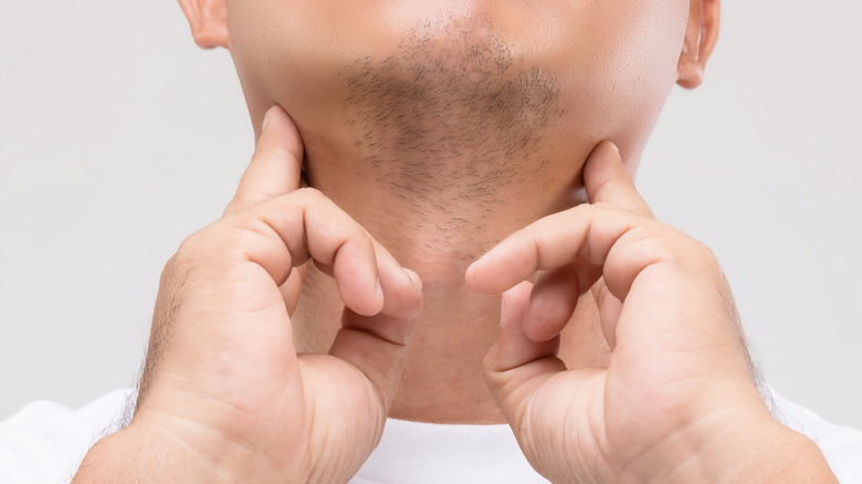 young man feeling for a swollen lymph node under his armpit 