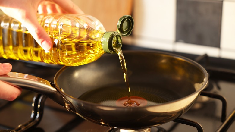 woman pouring oil into pan