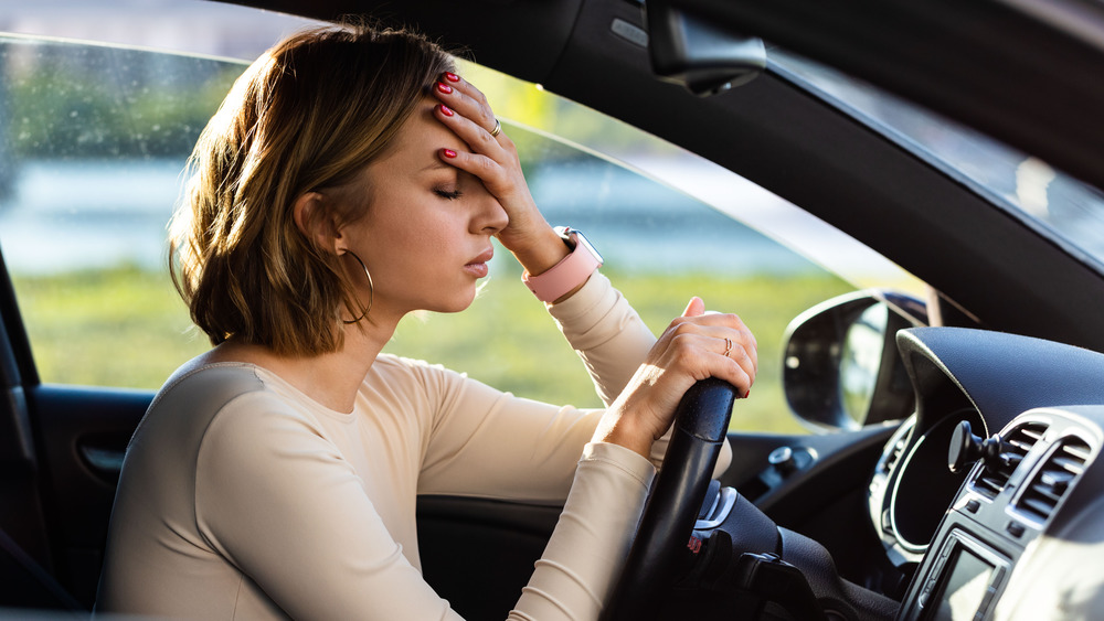 Tired woman touching face in car