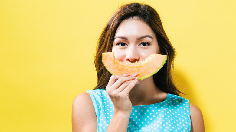 Woman smiling while holding a slice of cantaloupe