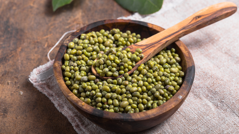 Wooden bowl and spoon containing unsprouted green mung beans