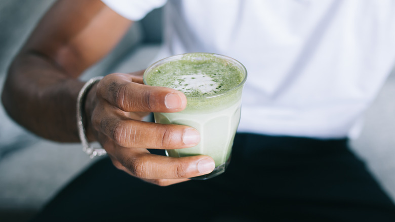 man holding green smoothie