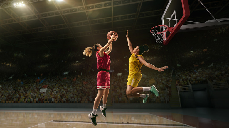 Basketball players battling for ball during air jump on court