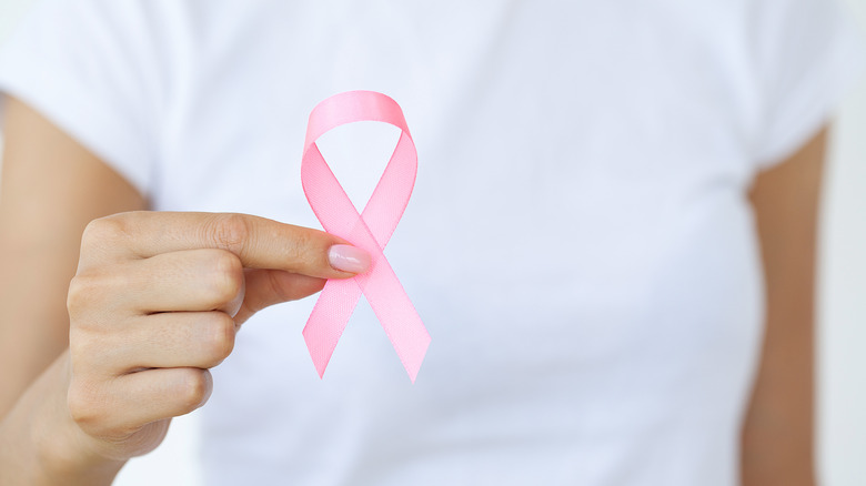 A woman holds a pink ribbon