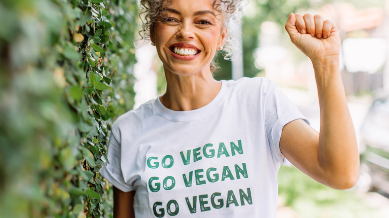 woman holding her arm up wearing a Go Vegan shirt