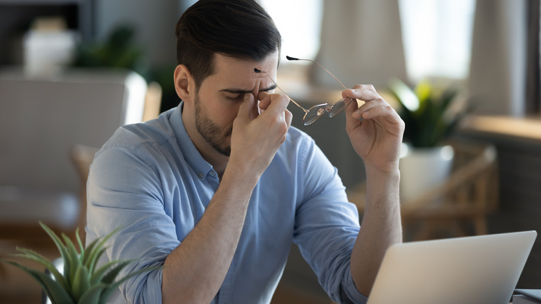 Man removing his glasses and rubbing his eyes 