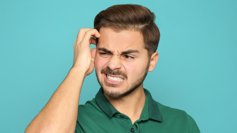 Irritated man scratching his head