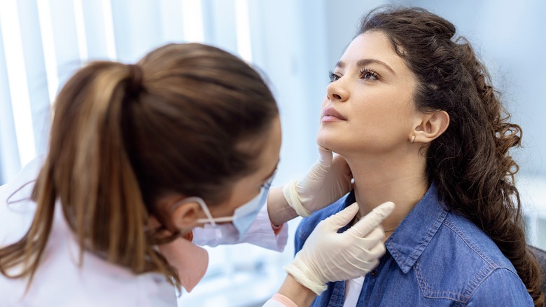physician examining patient's thyroid