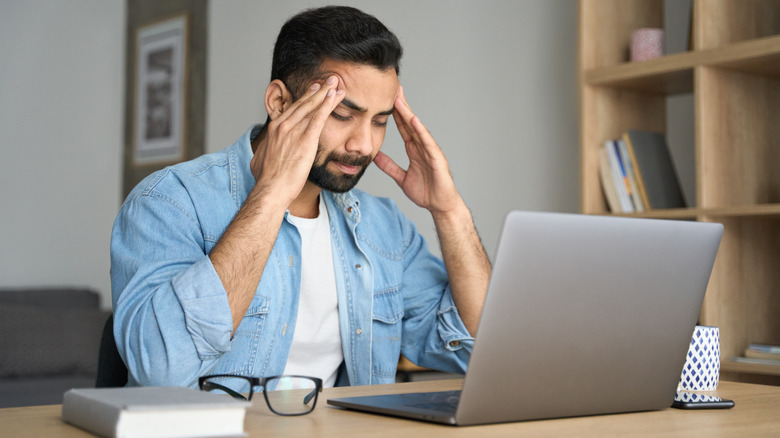 Person looking at computer screen with headache