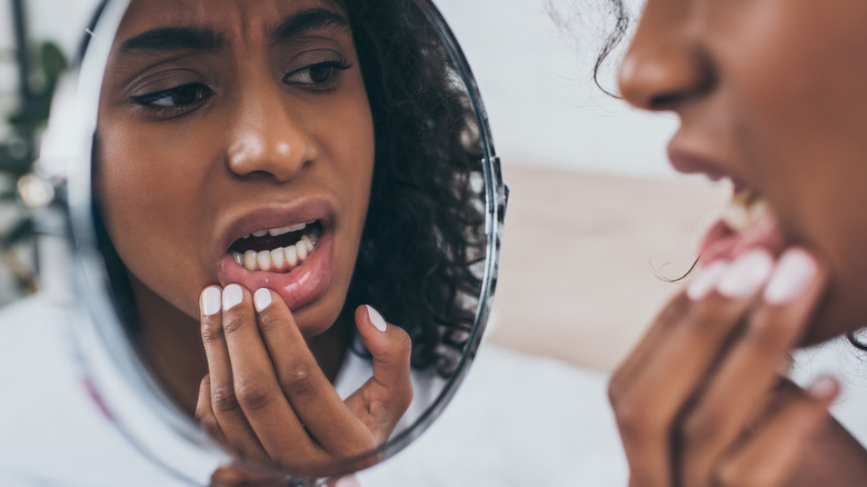 Woman examining teeth in mirror