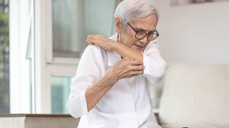 Older woman scratching her arm