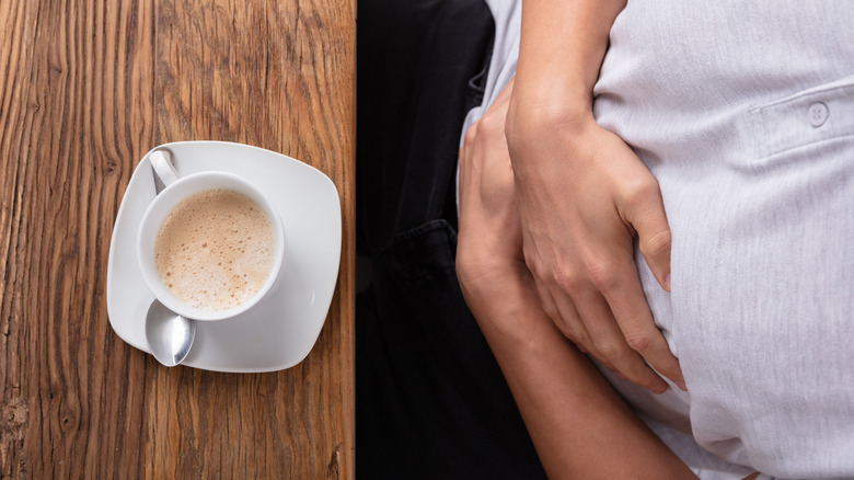 man with coffee holding stomach