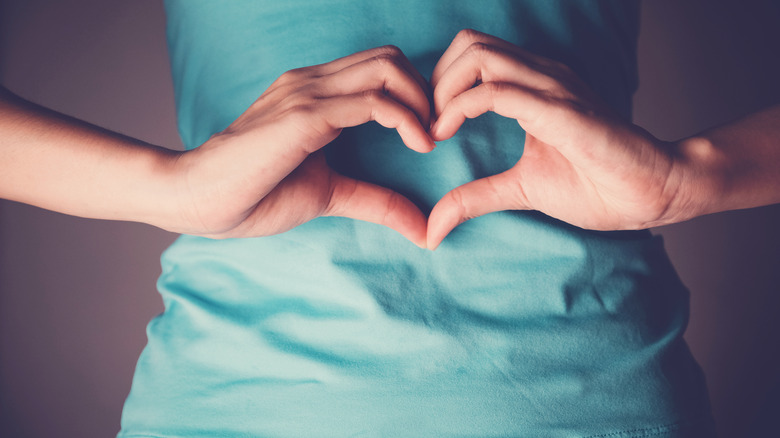 Woman making a heart shape on her belly