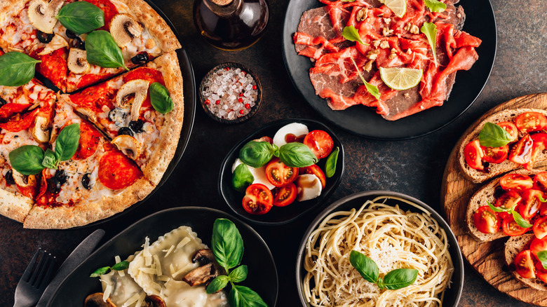 a table filled with pizza, pasta, and meat