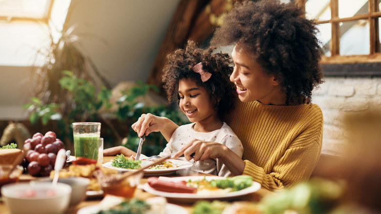 a mother and daughter eating together at the table 