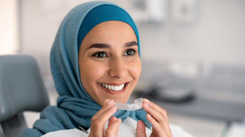 A woman holds Invisalign aligners