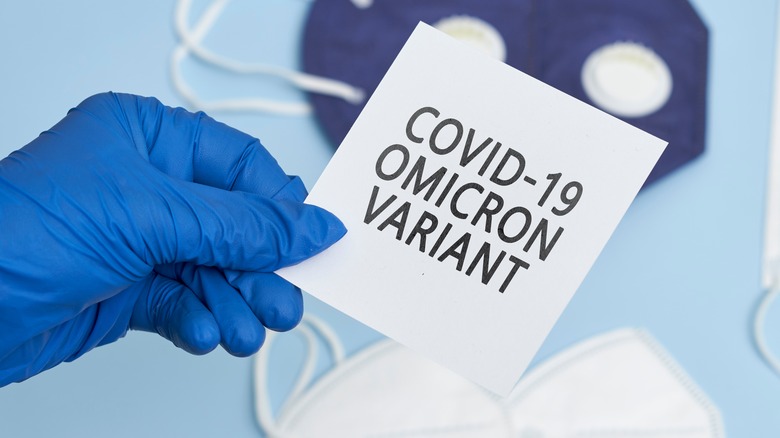 Person with gloves holding a sign that says "COVID-19 omicron variant"