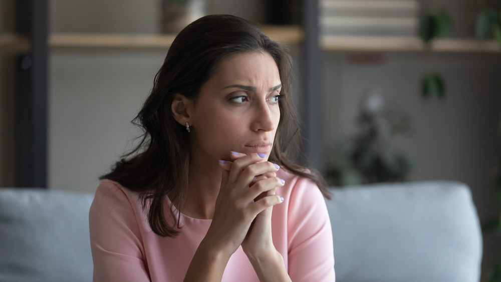 Woman sitting on couch at home looking worried