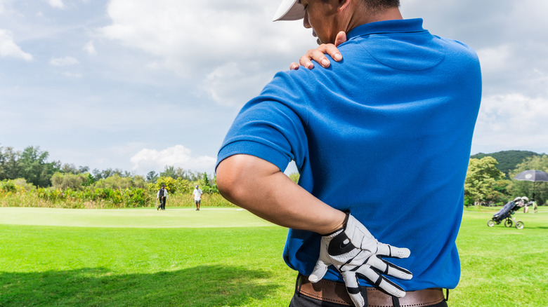 a golfer holds his lower back 