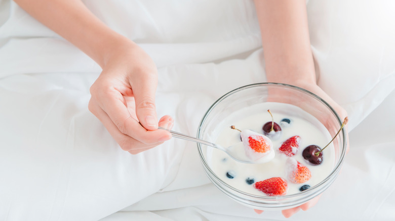 Hands holding bowl of yogurt and fruit