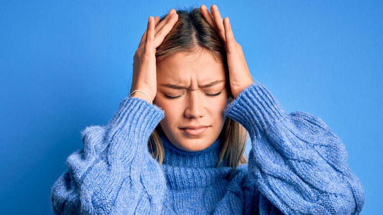 woman holding head in hands