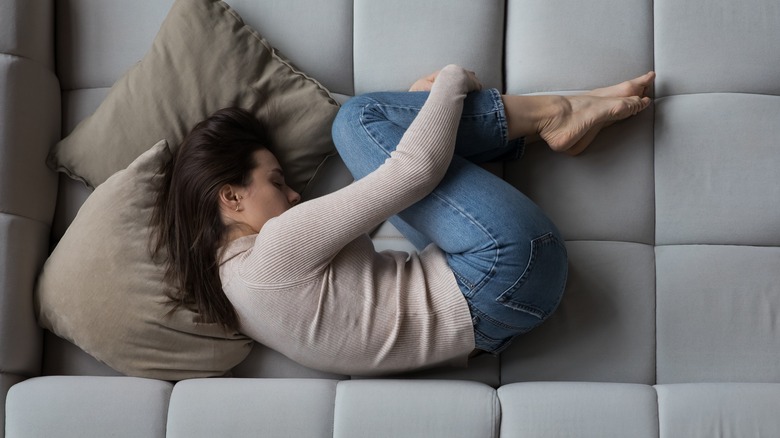 depressed woman curled up on bed