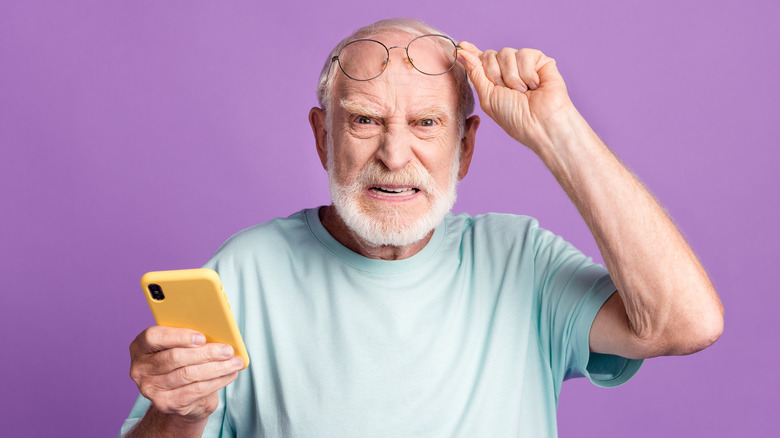 cranky old man holding cell phone