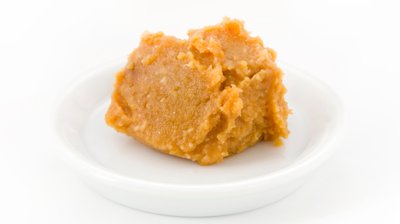 Yellow miso paste on a white dish against a white background