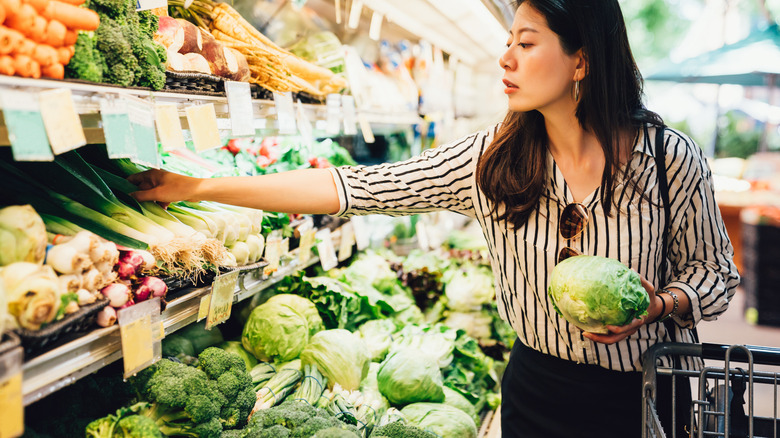 woman picking green leafy vegetables from store