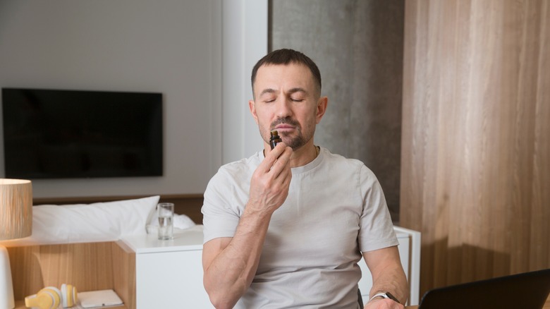 man smelling bottle of essential oil