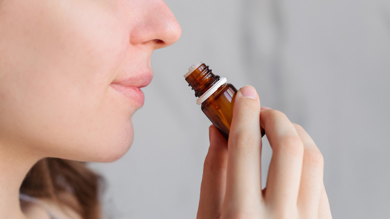 A girl is smelling a bottle of eucalyptus oil