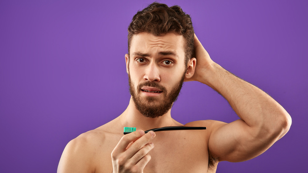 Man with toothbrush, looking confused