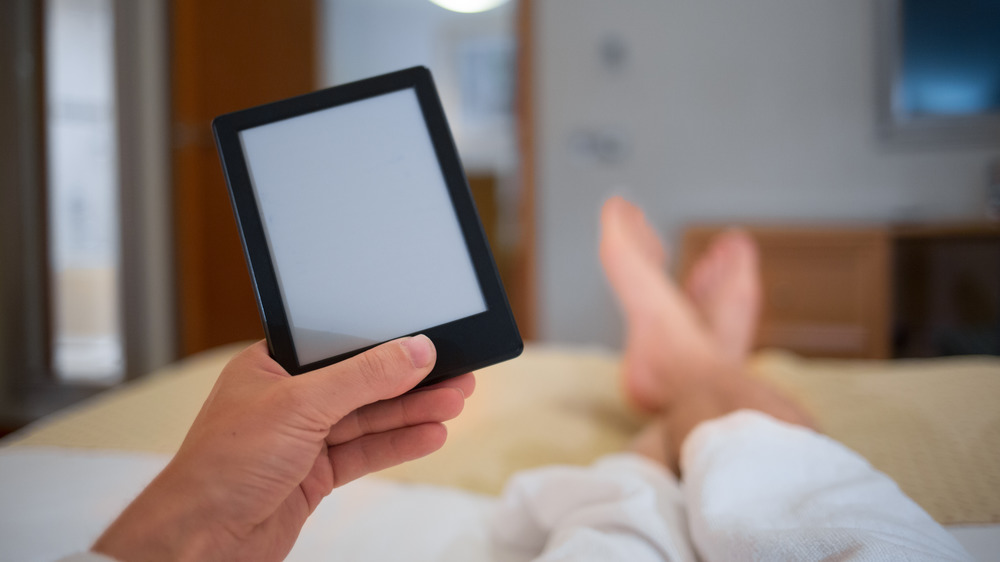 hands holding a Kindle in bed