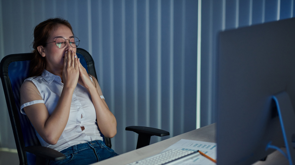 woman yawning in front of computer